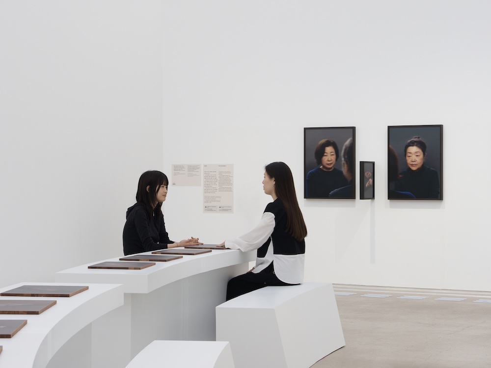 작가, 천경우. 작품명, 의지하거나 의지되거나. 부문, 사진과 설치. 제작년도, 2025년. 매체 및 기법, 퍼포먼스를 바탕으로 한 트립틱 사진과 설치, 아카이벌 피그먼트 프린트, 원목액자에 디본드와 플렉시글라스 페이스 마운트, 가변크기. 국립현대미술관 제작지원. 세 부분으로 구성된 9점의 사진. 이미지는 세 부분으로 나누어져 있다. 첫 번째 이미지와 마지막 이미지는 누군가를 바라보고 있는 나이든 여성의 얼굴을 보여준다. 가운데 이미지는 맞잡은 두 손을 보여준다.