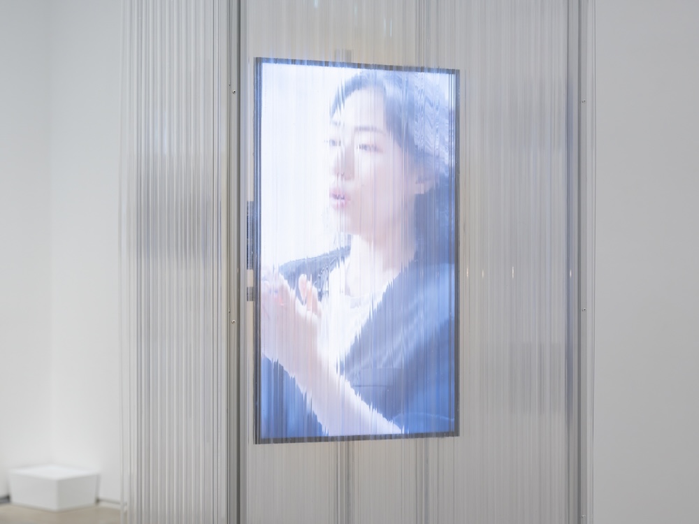 작가, 김은설. 작품명, 흐려지는 소리, 남겨진 소리. 부분, 설치. 제작년도, 2025년. 매체 및 기법, 모니터, 미디어 플레이어, 진동 스피커, 앰프, 폴리카보네이트. 규격, 가변 크기. 국립현대미술관 제작지원. 영상 스틸. 노트북 앞에 핸드폰이 놓여 있다. 노트북과, 핸드폰 화면, 이미지 하단에 각각 자막이 있다. 세 자막은 ‘밑에’로 시작되는 동일한 문장을 표시하고 있다. 하지만 속도는 달라서, 어떤 화면에는 좀더 빠르게, 다른 화면에는 좀더 느리게 자막이 나타난다.